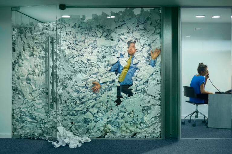 person trapped in office full of documents