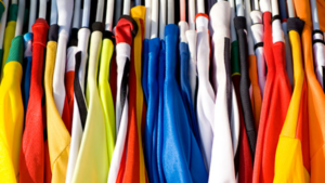 Colourful work uniforms hanging closely together on a clothing rack.